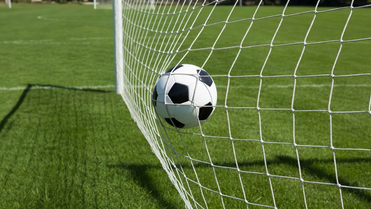 Soccer ball striking the back of a white goal net in daylight
