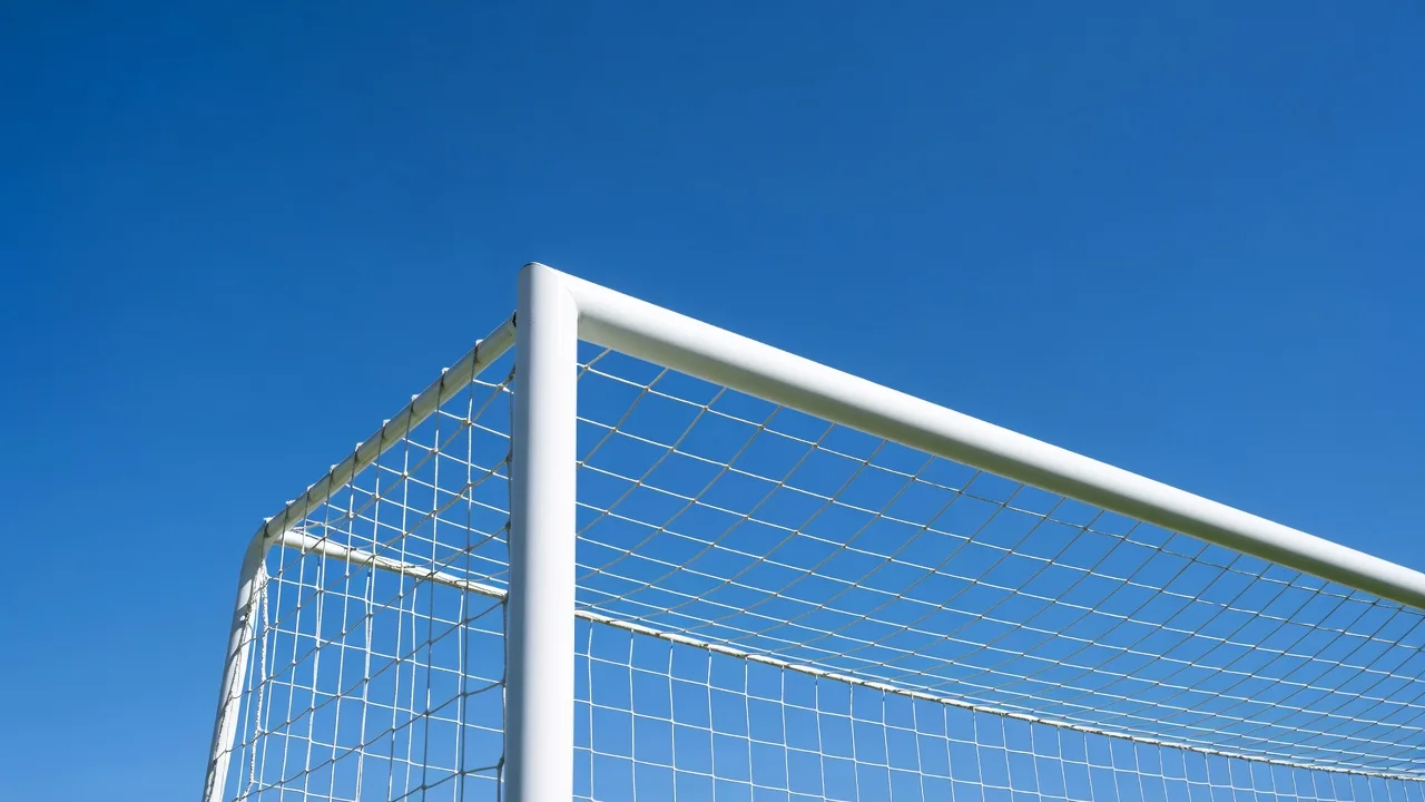 Goal frame corner with white net against a vivid blue sky