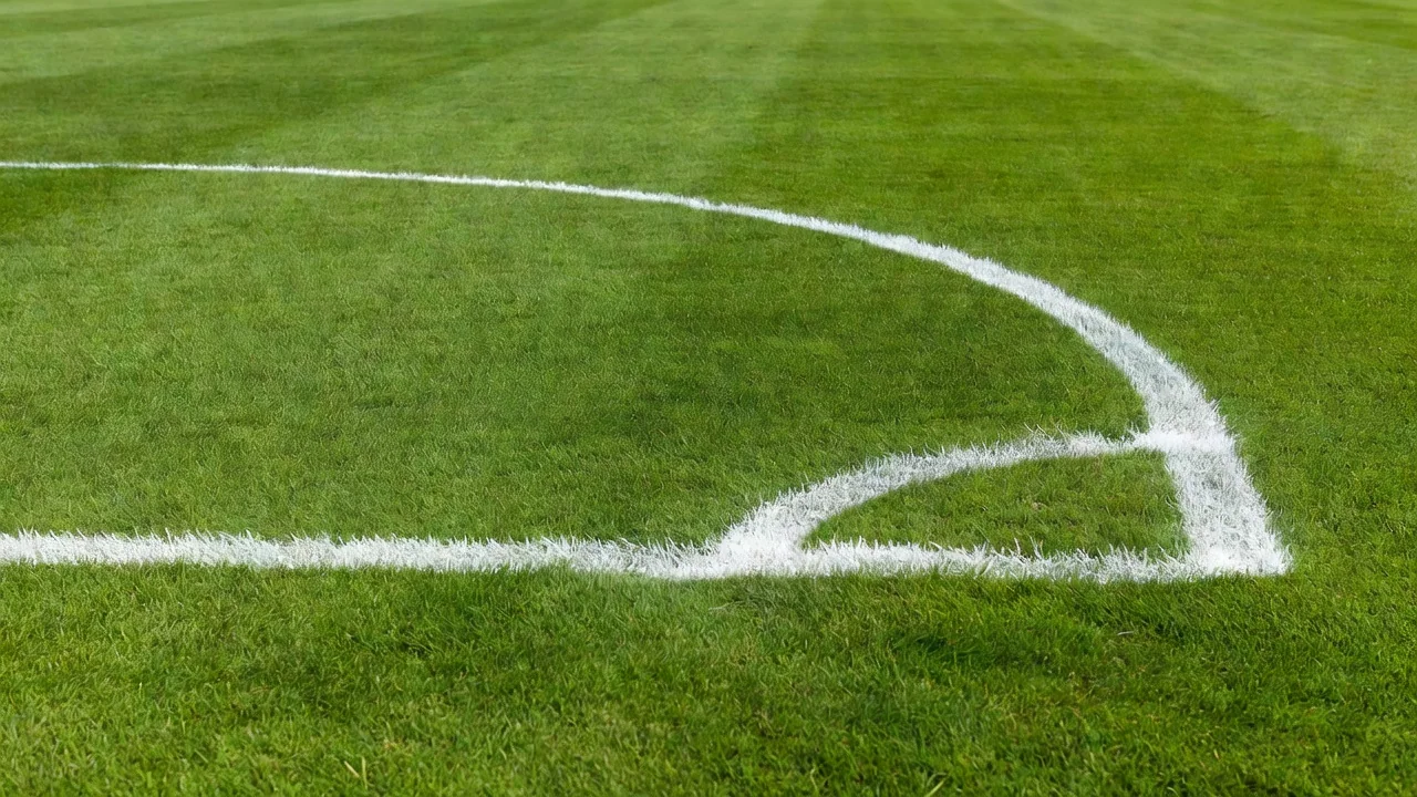 Single football boot hanging by its laces on a bright wooden peg