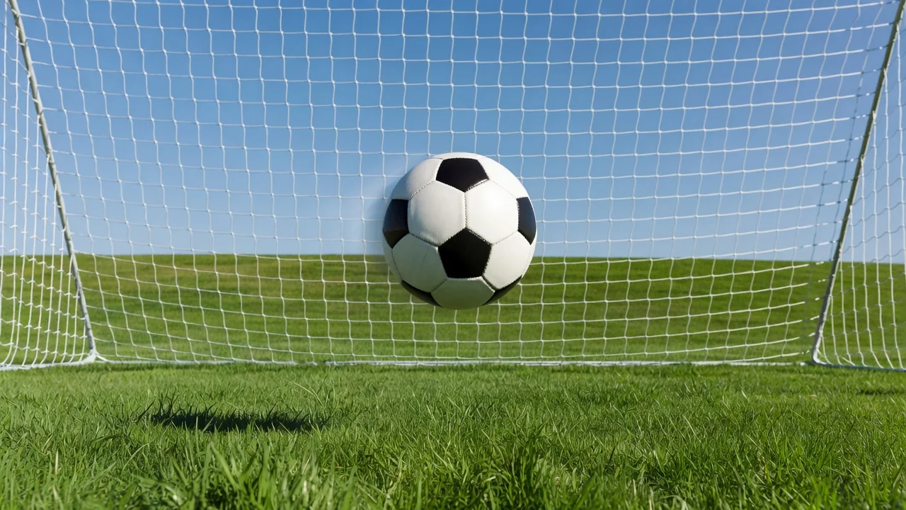 Football frozen mid-flight toward a goal in bright daylight